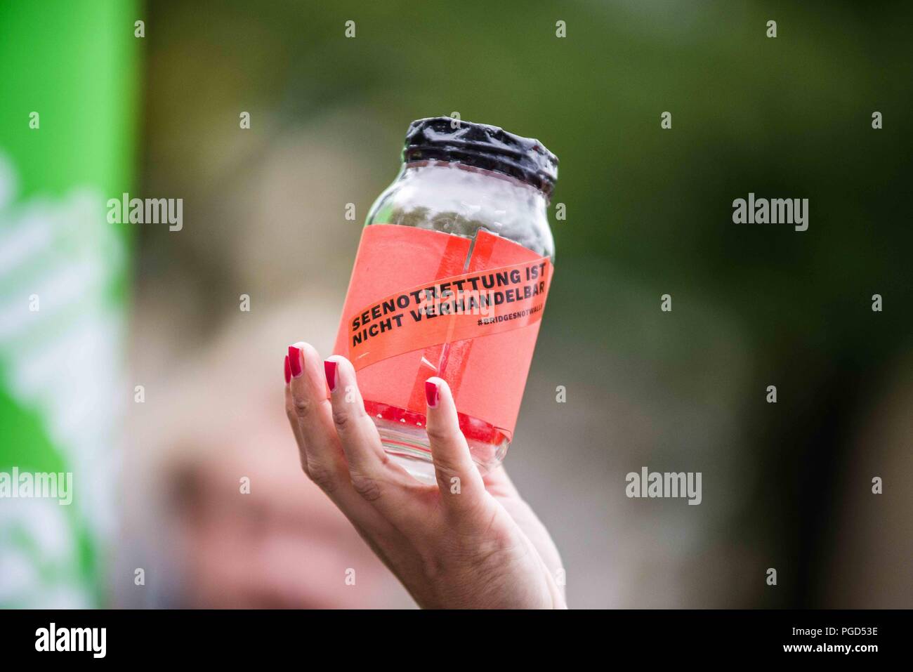 Munich, Bavaria, Germany. 25th Aug, 2018. ''Sea rescues are non-negotiable'' on a donation jar. Under the motto of 'Sea Rescue is NOT Negotiable'', over 1000 took to the streets of Munich to demand a stop to the criminalizations of sea rescues of stranded migrants and refugees in the Mediterranean Sea. Recent shifts in politics, particularly those brought about by Bavaria's Horst Seehofer, Italy's Salvini, Hungary's Viktor Orban, and Austria's Sebastian Kurz have resulted in rescue ships being denied port access and fuel, and resulted in the confiscation of the Mission Lifelin Stock Photo