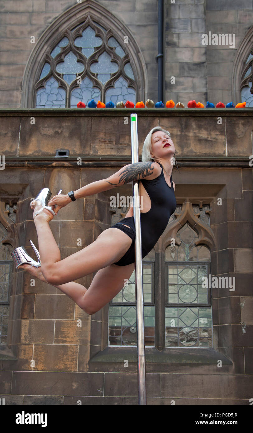 Edinburgh, Scotland, UK. 25 August 2018. Edinburgh Fringe Royal Mile, on the final Saturday there was a lot of hanging around on the High Street not for acts but by acts displaying their agility on Poles, skilled female performer 'Professional Wild Thing' Bex Crow on her flying pole busked in the alcoves Stock Photo