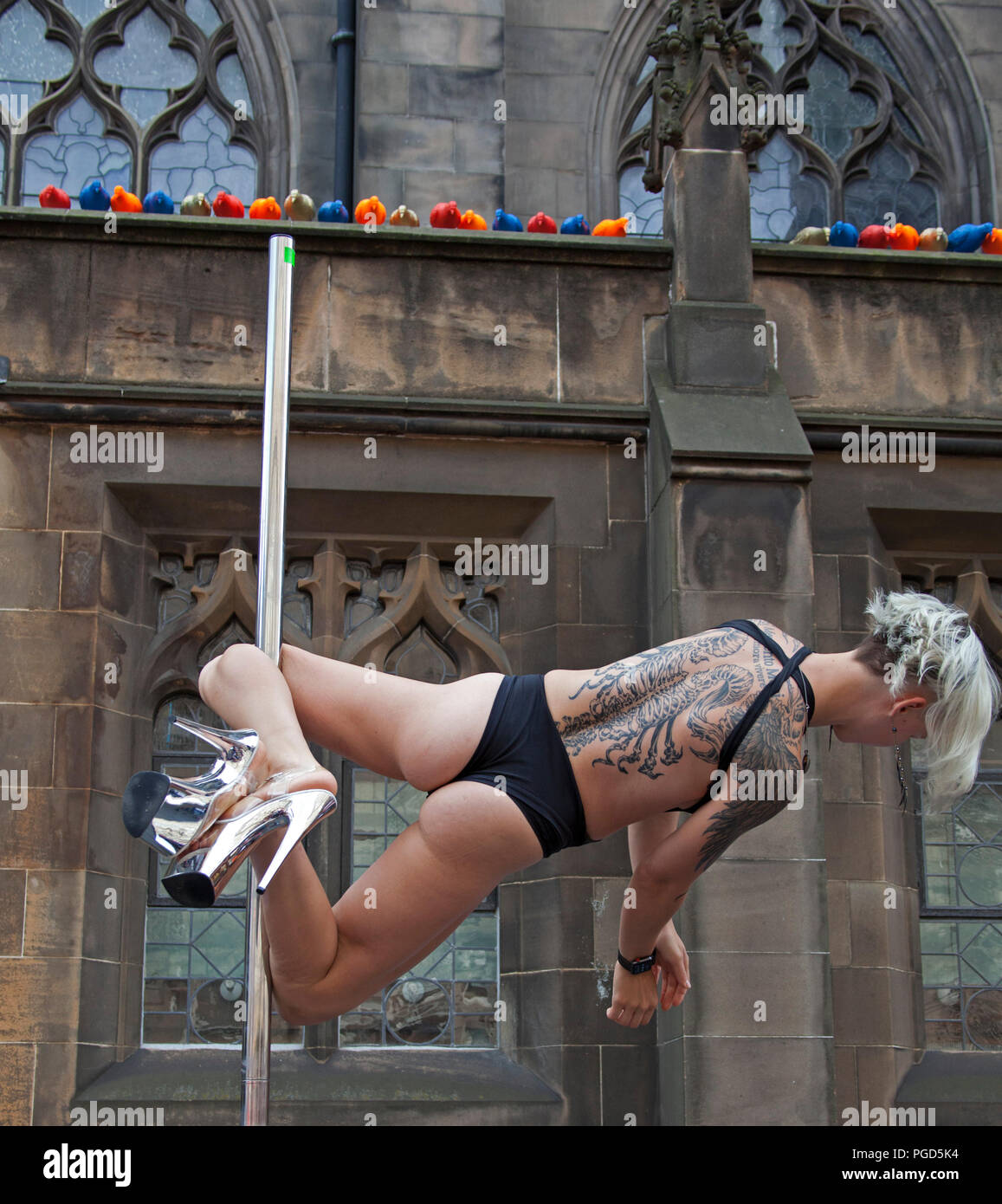 Edinburgh, Scotland, UK. 25 August 2018. Edinburgh Fringe Royal Mile, on the final Saturday there was a lot of hanging around on the High Street not for acts but by acts displaying their agility on Poles, skilled female performer 'Professional Wild Thing' Bex Crow on her flying pole busked in the alcoves Stock Photo