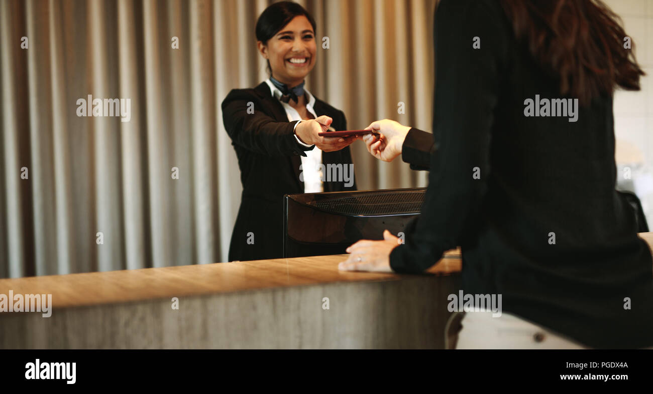 Smiling female concierge returning the documents to hotel guest after