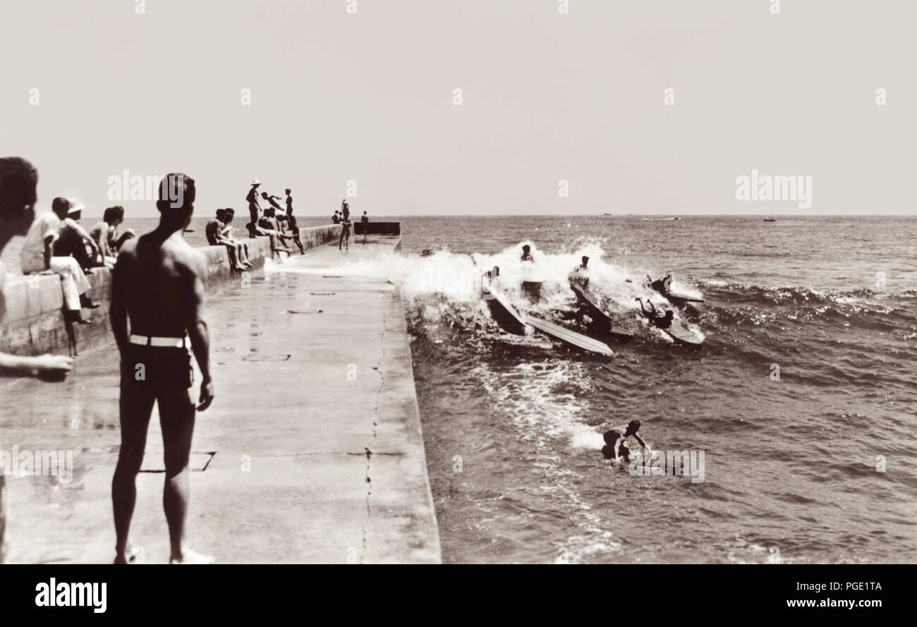 California surfers catching a wave along the Newport Harbor jetty in Corona del Mar in the early 1930s. This famous spot in surfing history was home of the Corona del Mar Surfboard Club, formed in 1928 with members including Hawaii's Duke Kahanamoku, Redondo's Tom Blake, Gene 'Tarzan' Smith, and Gerard and Art Vultee of the Los Angeles Athletic Club. It was also the site of one of the first surfing championships on the US mainland, the Pacific Coast Surfboard Championship, which began in 1928. Stock Photo