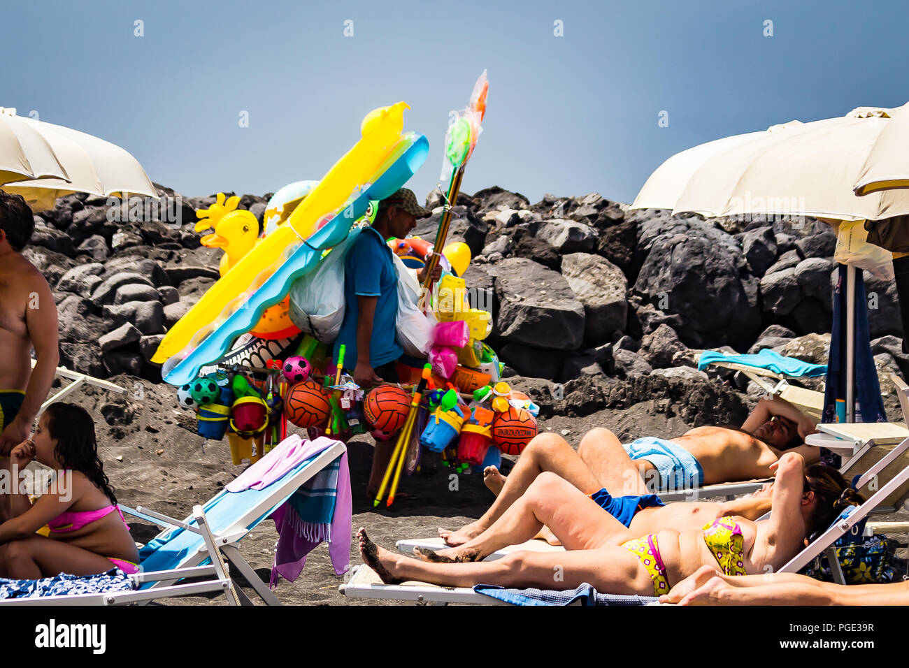 Torre del Greco, near Naples, Italy - June 3, 2018 - a man sells inflatable matresses and balls on a beach Stock Photo