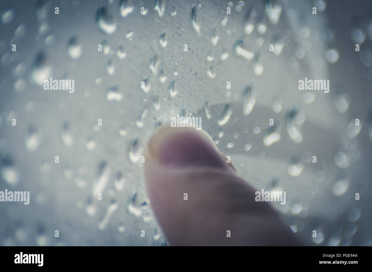 Moody Feelings Concept: Finger Of A Teenager Drawing On The Window With Raindrops On A Rainy Day Stock Photo