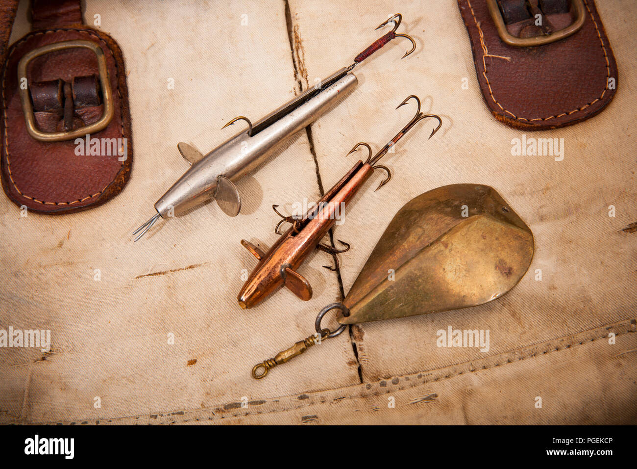Two old metal Devon minnow lures with hooks and an old metal fishing spoon  lure displayed on an old fishing tackle bag. From a collection of vintage f  Stock Photo - Alamy
