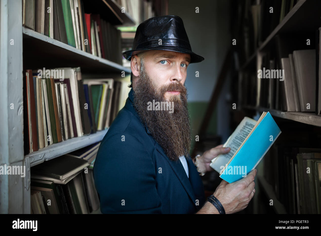 Stylish bearded man with book in library. education, university concept Stock Photo