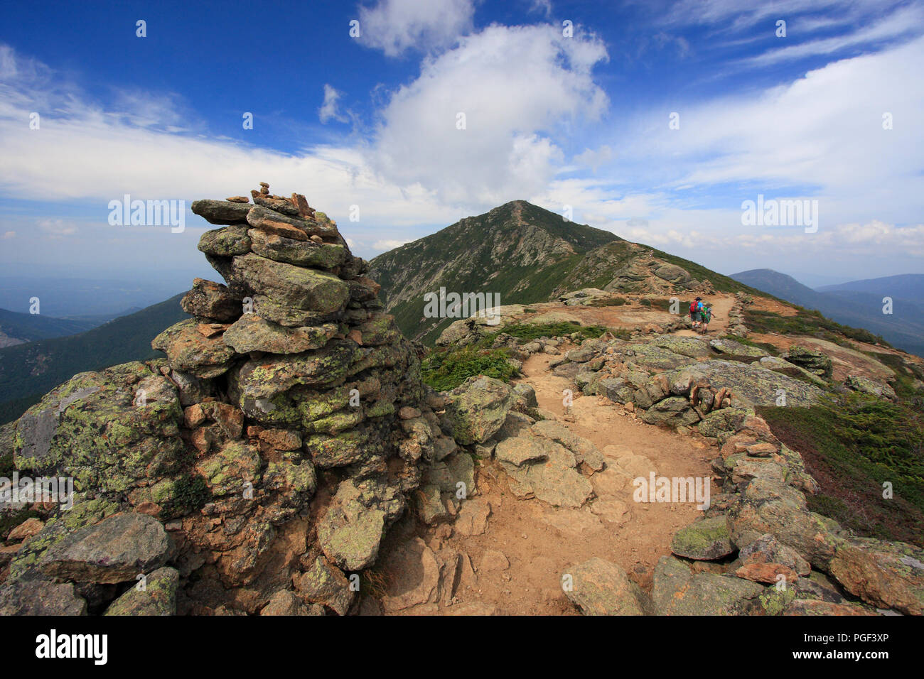 Hikers trekking along Franconia mountain ridge traverse, with a beautiful landscape background and blue sky. Mount Lafayette, Mount Lincoln, N H Stock Photo
