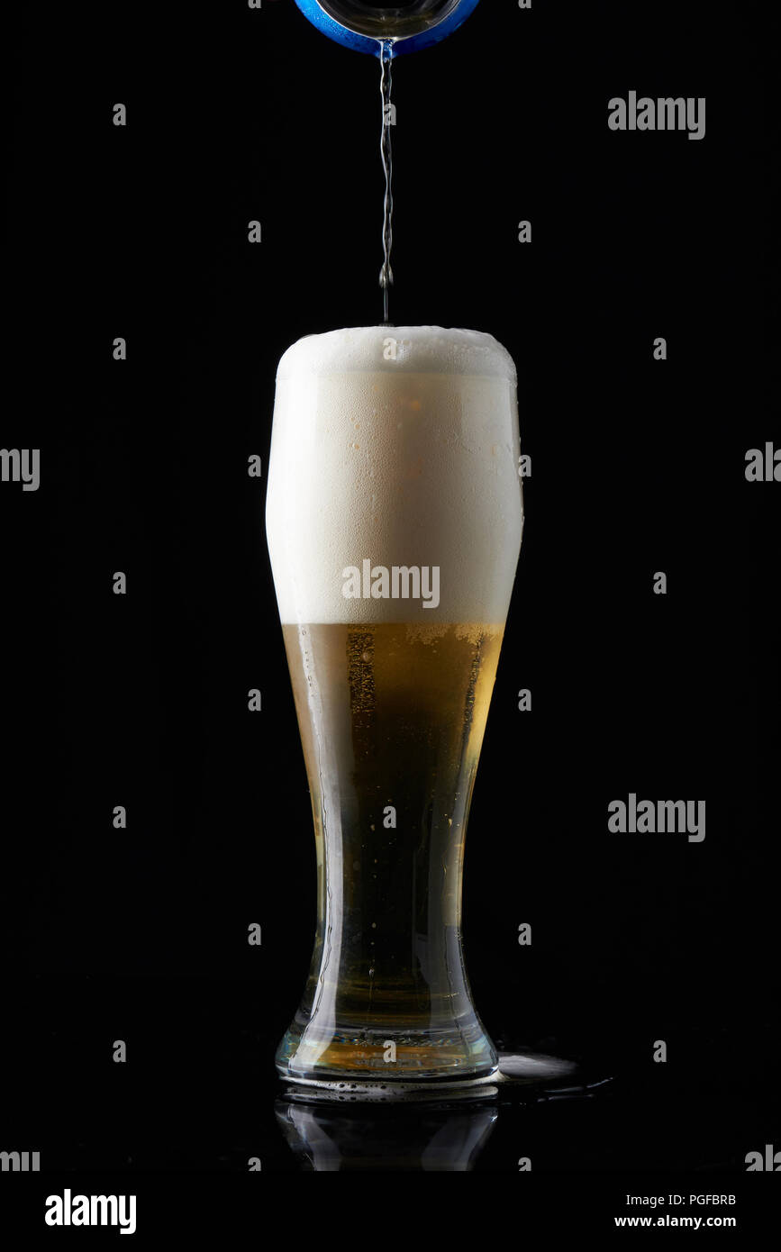 Pour beer in tall glass isolated on black background Stock Photo