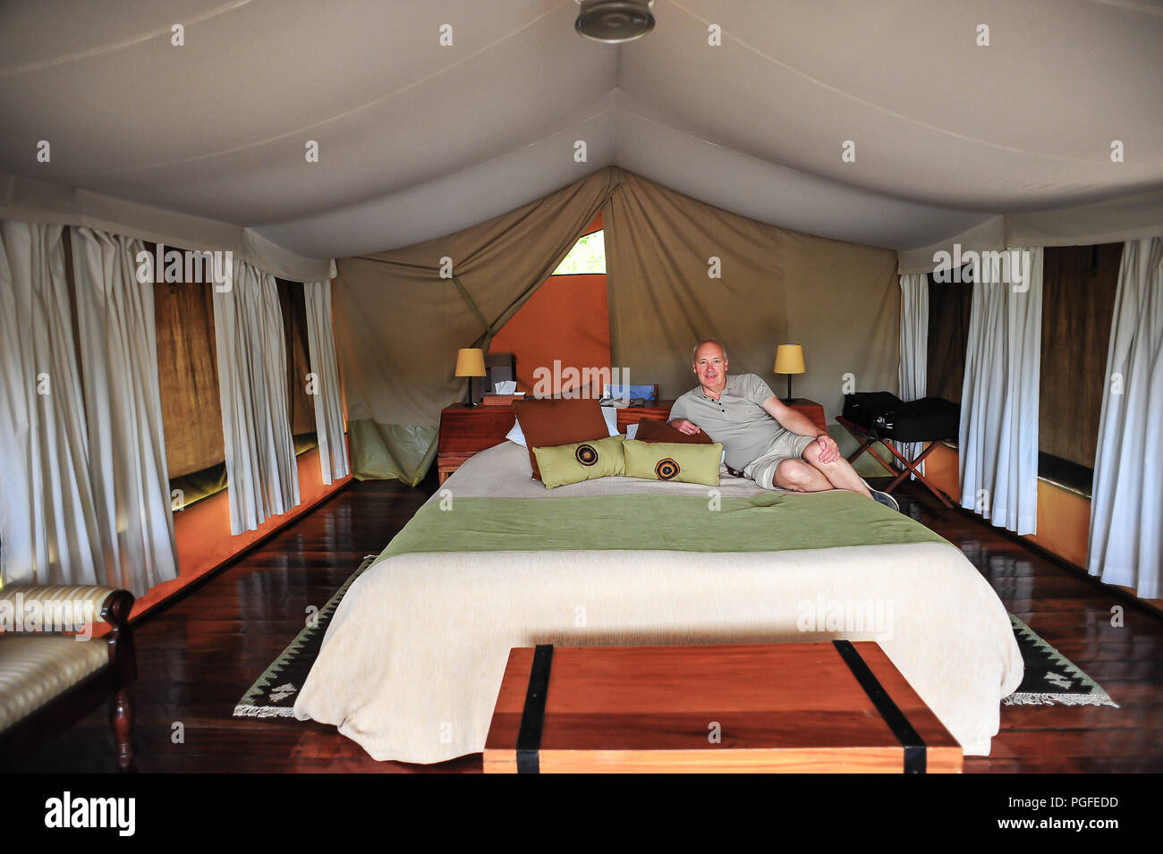 Man relaxing inside of a luxury tent in a safari campsite, Masai Mara, Kenya,  Africa. Stock Photo