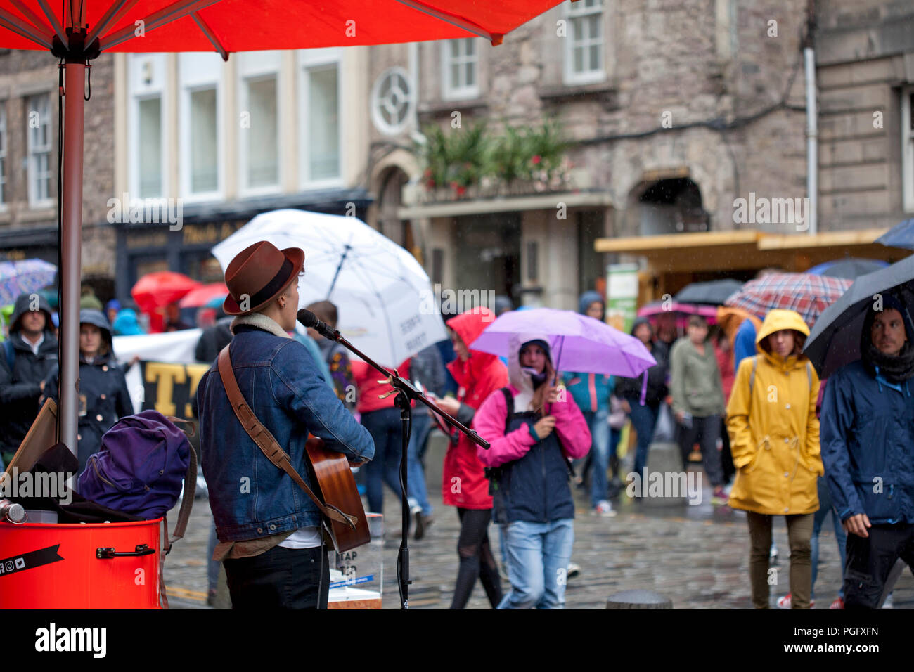 Edinburgh, Scotland, Uk. 26 August 2018. Weather Edinburgh Fringe on Royal Mile, Final Sunday heavy rain fell but the show goes on with  busker singer 'TashBird' singing in the rain Stock Photo