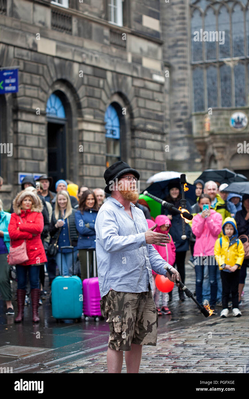Edinburgh, Scotland, Uk. 26 August 2018. Weather Edinburgh Fringe on Royal Mile, Final Sunday heavy rain fell but the show goes on with  a performer juggling fire. Stock Photo