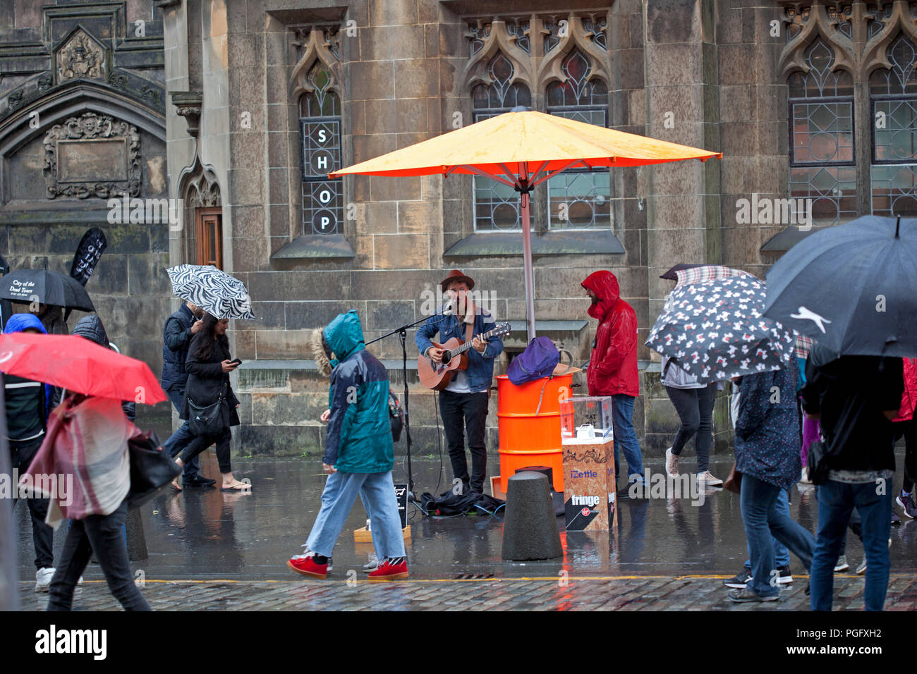 Edinburgh, Scotland, Uk. 26 August 2018. Weather Edinburgh Fringe on Royal Mile, Final Sunday heavy rain fell but the show goes on with  and busker singer 'TashBird' singing in the rain Stock Photo