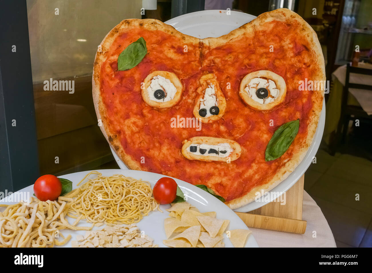 Funny face shape pizza on display, as advertising, outside an italian
