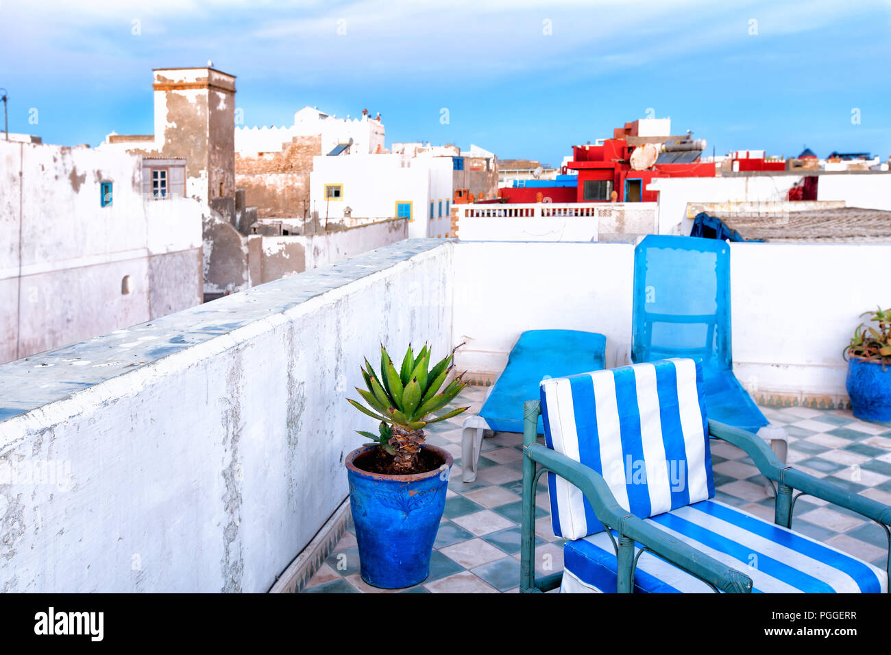 Morocco, whitewashed rooftops in the seaside village of Essaouira. In the foreground, a blue and white tiled roof with deck chairs. Stock Photo