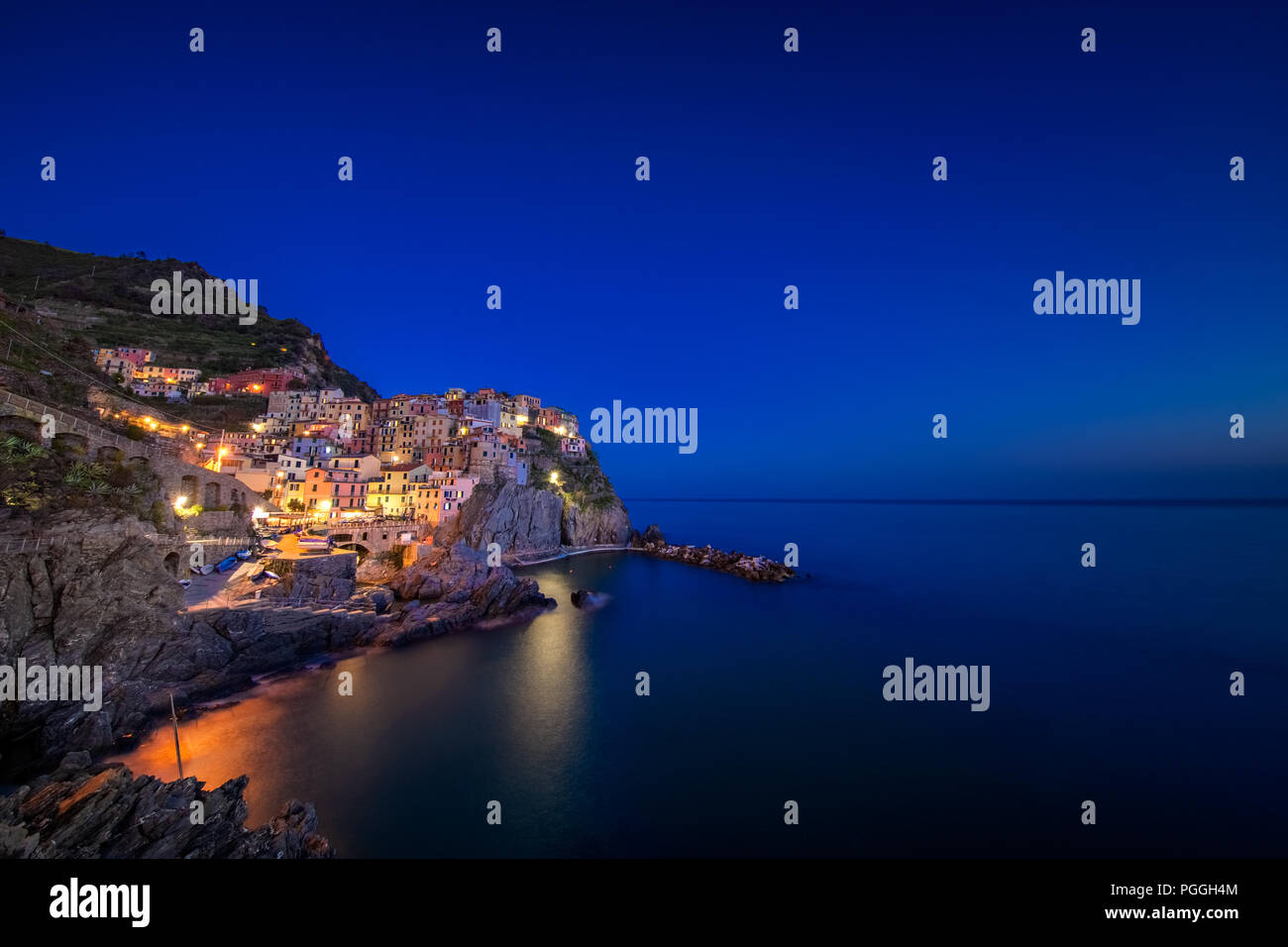The town of Manarola, with lights on, built upon a cliff above the Mediterranean Sea and one of the five cinque terre villages near La Spezia, Italy. Stock Photo