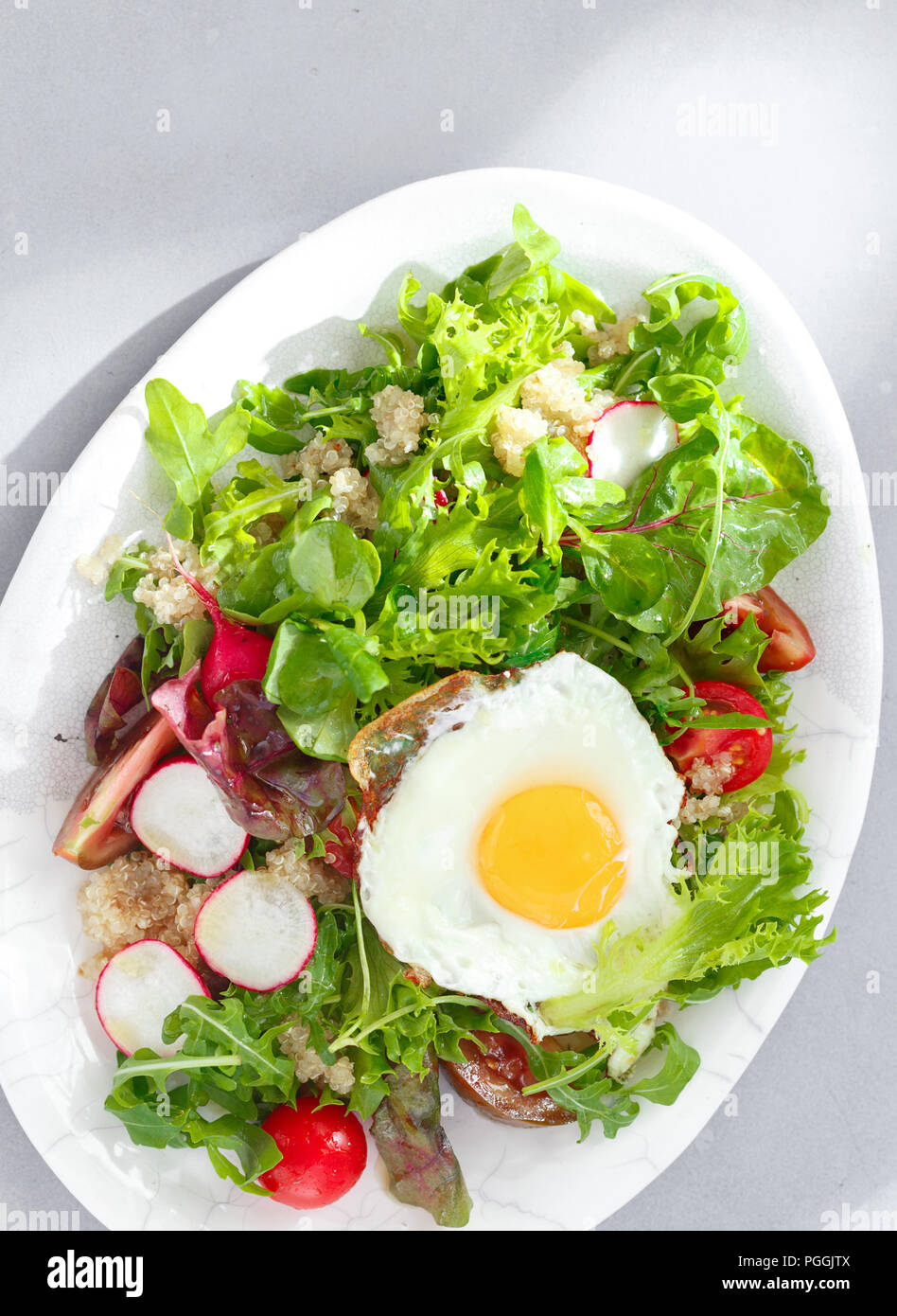 Plate fresh salad with quinoa and fried egg on gray concrete background top view. Healthy food clean eating Stock Photo