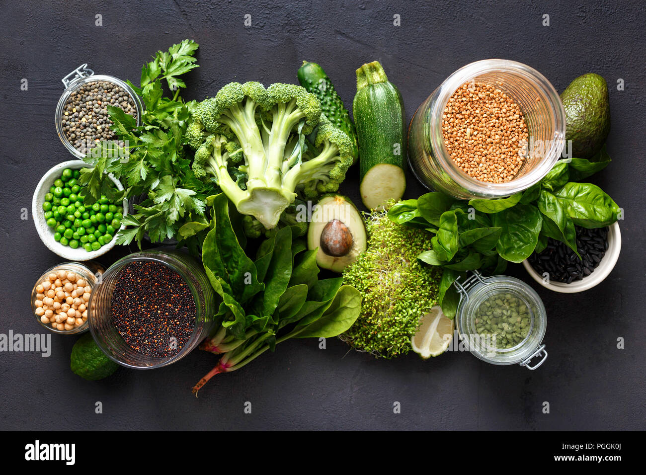 Raw healthy food clean eating vegetables and grain products: green vegetables, quinoa, chickpea, beans, buckwheat, green lentils on dark stone backgro Stock Photo