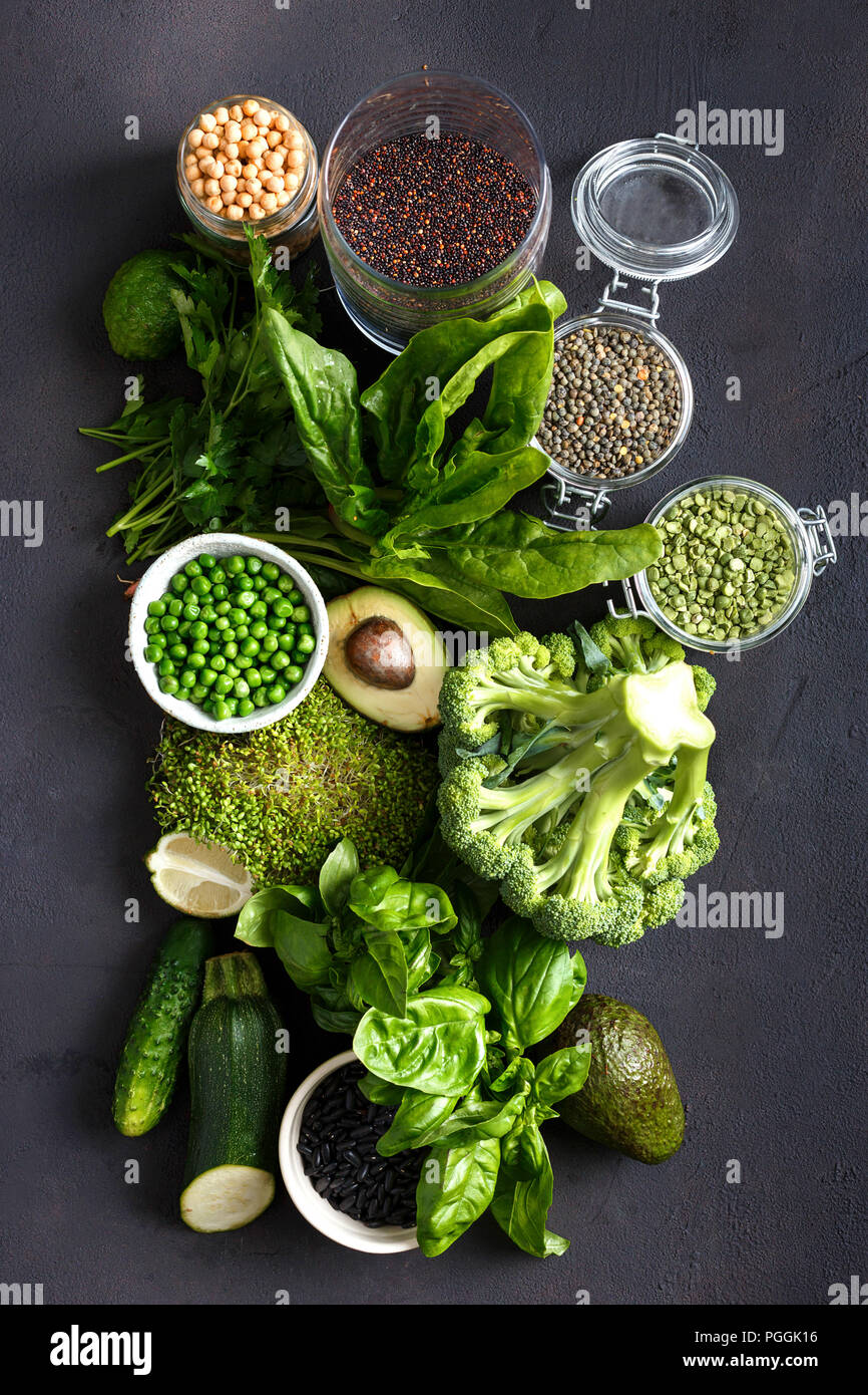 Raw healthy food clean eating vegetables and grain products: green vegetables, quinoa, chickpea, beans, buckwheat, green lentils on dark stone backgro Stock Photo