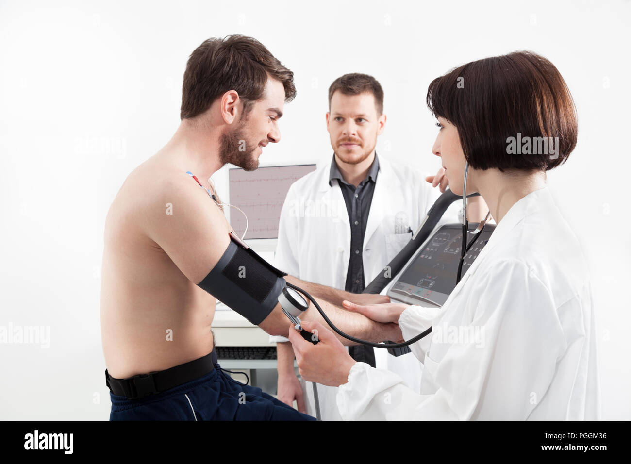 A male patient, pedaling on a bicycle ergometer stress test system for the function of his heart checked Stock Photo