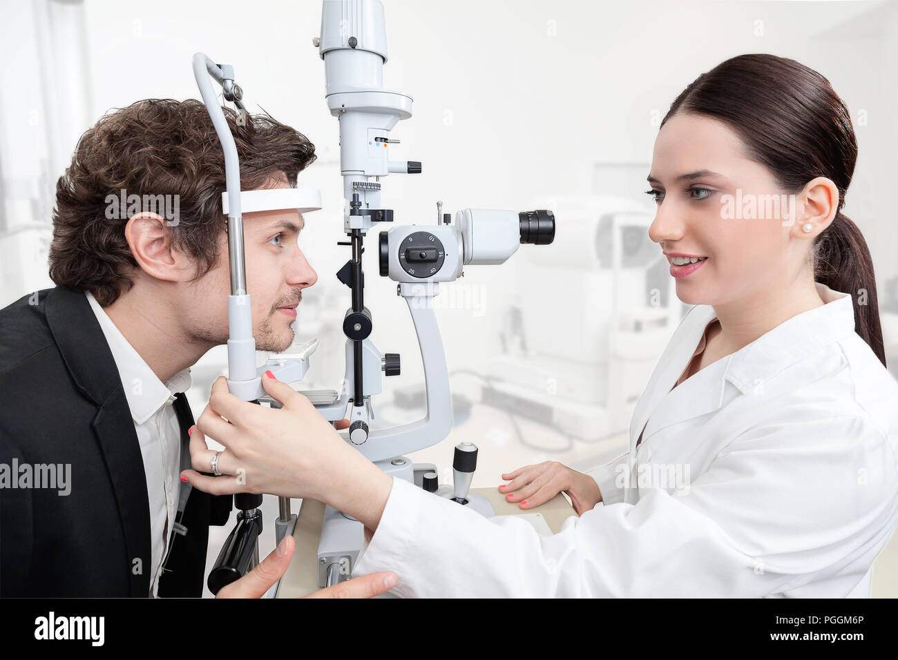 Eye Woman Doctor Adjusting Slit Lamp / handsome man during a cornea exam / the oculist in eyes clinic doing crystalline lens diagnostic / high technol Stock Photo