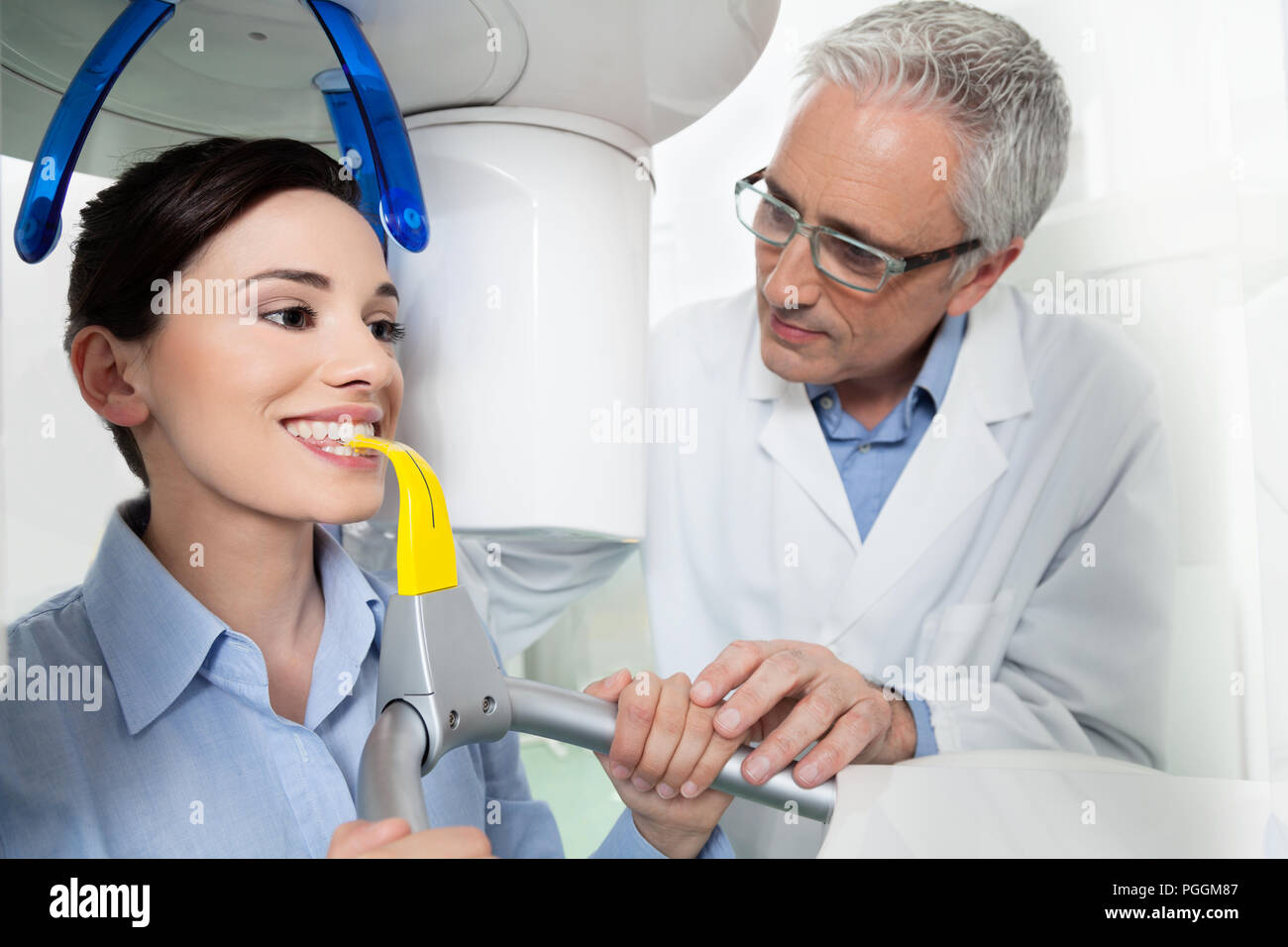 Young woman portrait having panoramic digital X-ray of her teeth with a middle age doctor in the dental office. Stock Photo