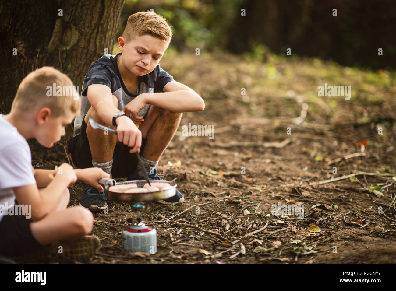 Boys cooking on camping stove outdoors Stock Photo - Alamy