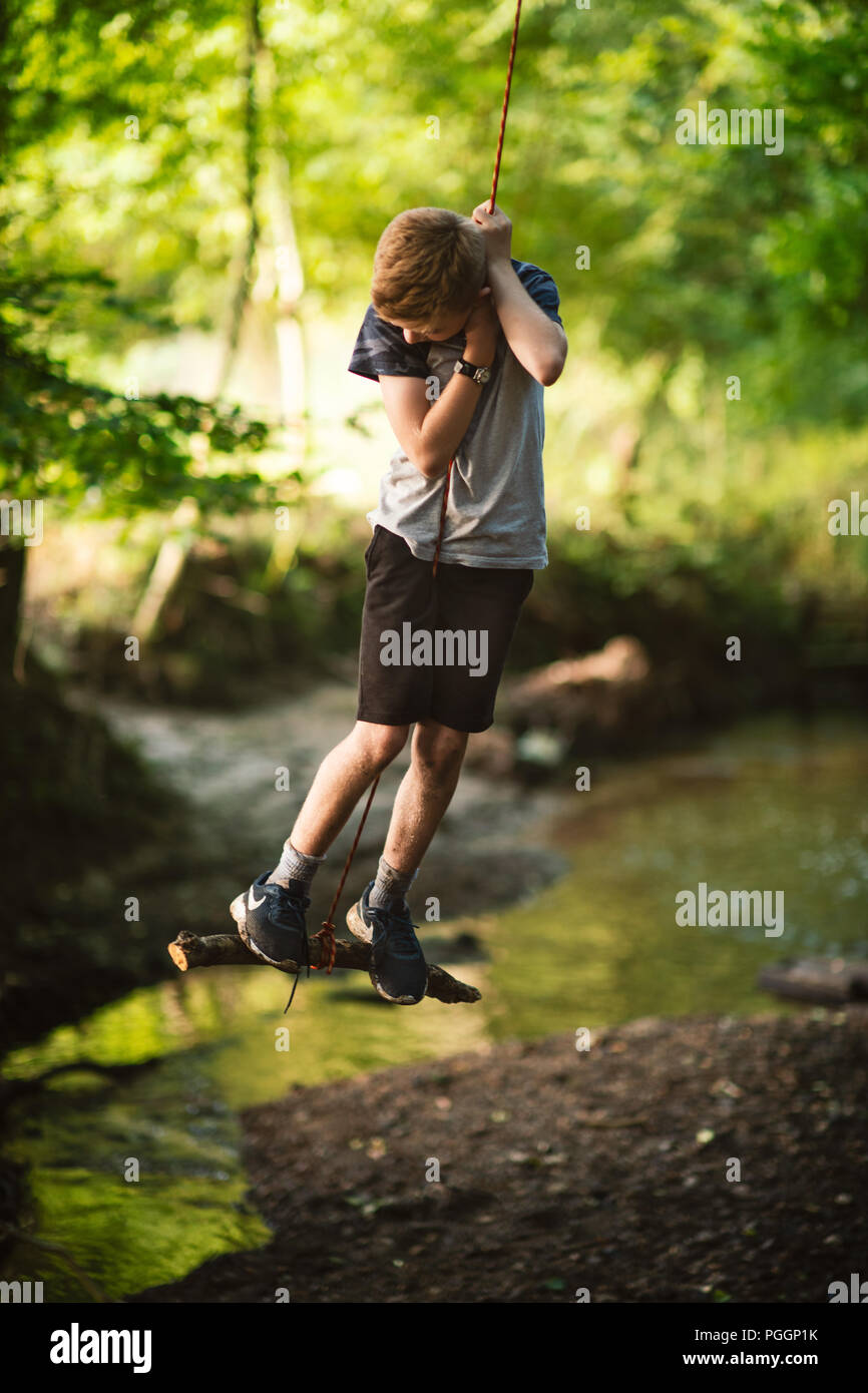 Boy swinging on rope swing Stock Photo Alamy