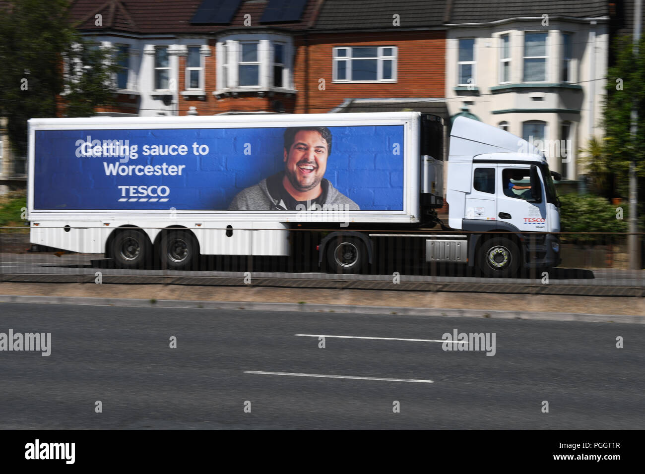 A Tesco truck driving along the road with Getting to Worcester advertising campaign on the side featuring a smiling male. Stock Photo
