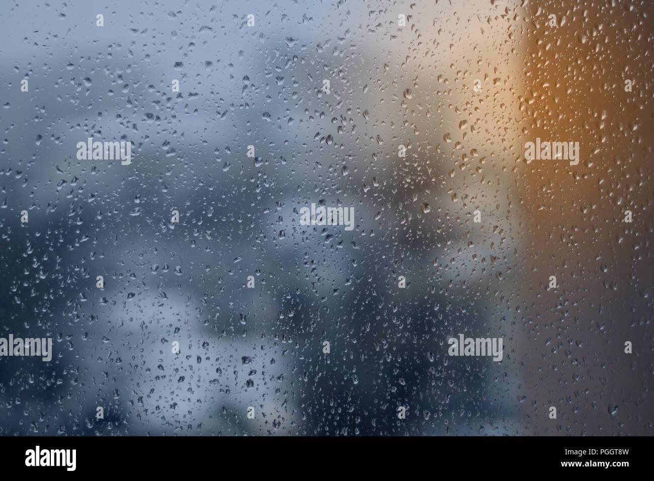 Abstract blue and yellow background, texture of rain drops on glass. Raindrops on window, rainy weather. Stock Photo
