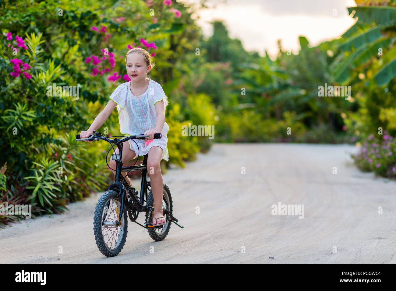 Cute girl biking at tropical island settings having fun Stock Photo