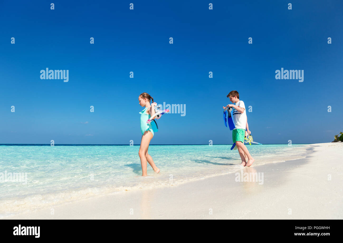 Little kids with snorkeling equipment on tropical beach having fun during summer vacation Stock Photo