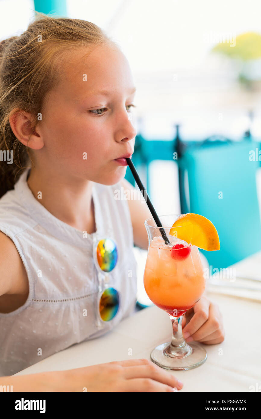 Adorable little girl drinking tropical juice mocktail at outdoor cafe on summer day Stock Photo