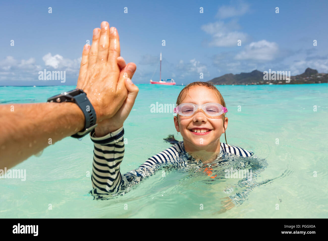 Split underwater photo of cute girl having fun with her father in tropical ocean Stock Photo
