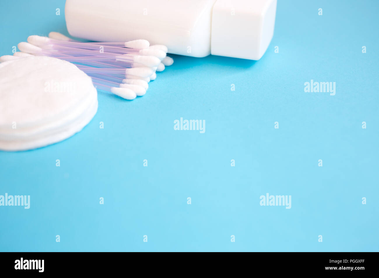 top view personal care products. white bottle, razor, ear sticks, cotton pads, toothbrush on blue background. copy space Stock Photo