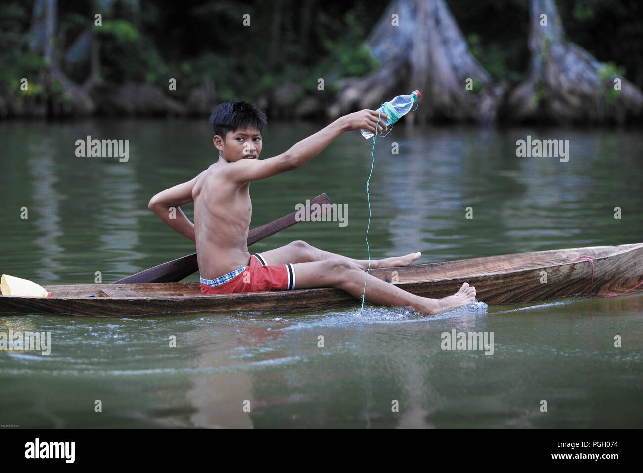 Boy fishing from wooden canoe in Monterrico, Guatemala Stock Photo