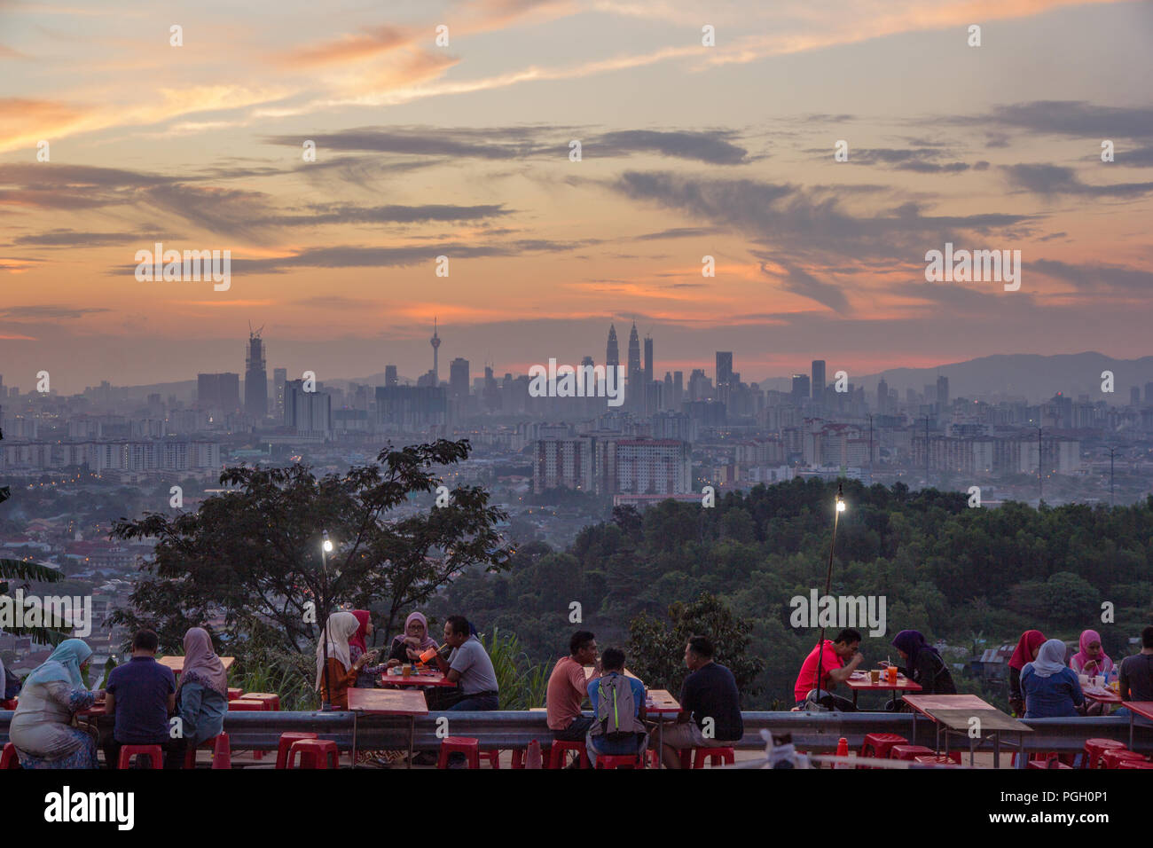 Iconic skyline of Kuala Lumpur at sunset with couples and friends enjoying the view and socialising in the foreground, Malaysia, circa September, 2017 Stock Photo