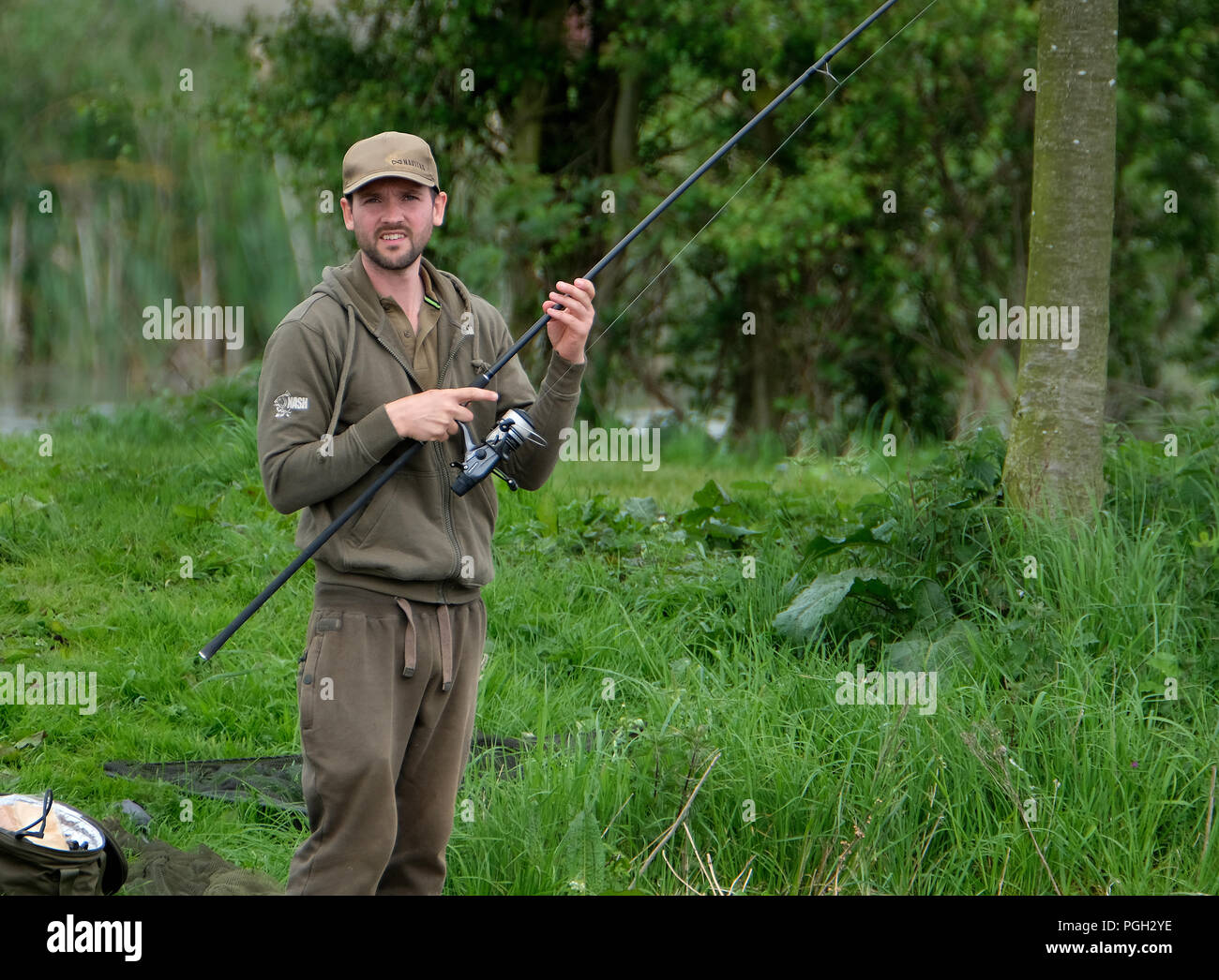 Angler with rod at fishing pond bank side. Stock Photo