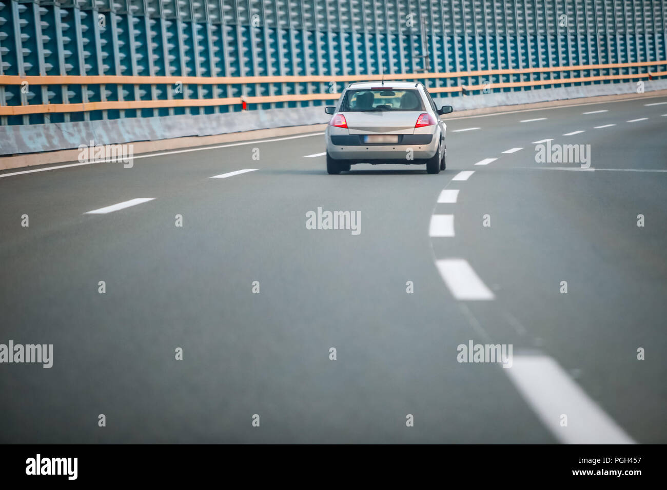 Rear view of car driving on the highway with noise barrier. Stock Photo
