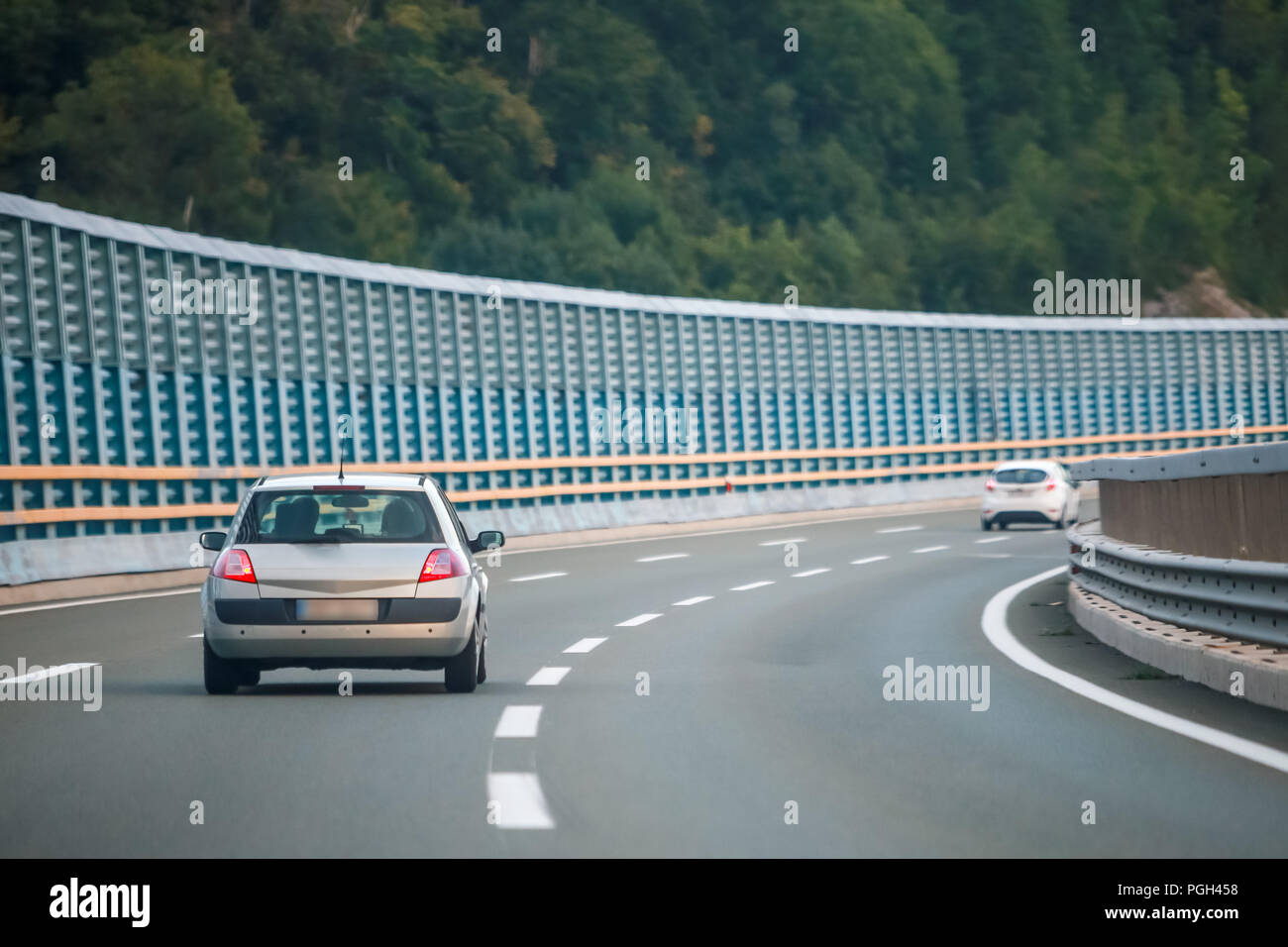 Rear view of car driving on the highway with noise barrier. Stock Photo