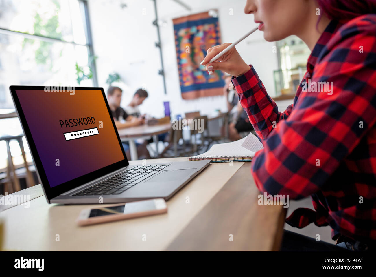 Side view of a young woman sitting in cafe, hand typing laptop computer with password login on screen. Cyber security concept Stock Photo