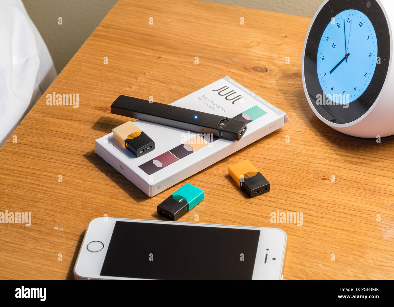 Box holding JUUL nicotine dispenser and pods on bedside table Stock Photo