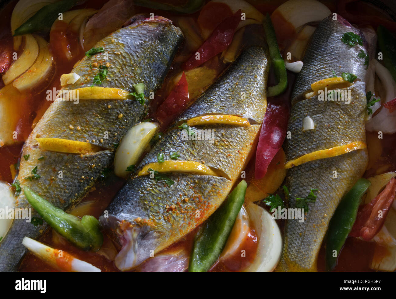 Sea bass prepared to put in the oven with lemon, pepper, onion and sauce Stock Photo