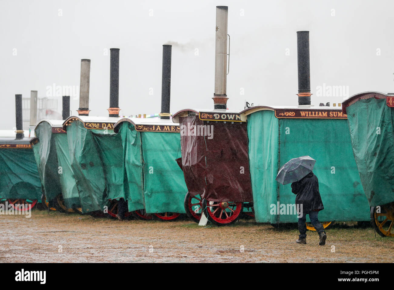 Burrell Showmans Road Locomotives under covers as a rain shower passes over the Great Dorset Steam Fair, in Blandford, Dorset, where hundreds of period steam traction engines and heavy mechanical equipment from all eras gathered for the annual fair to celebrate the 50th anniversary of the show. Stock Photo