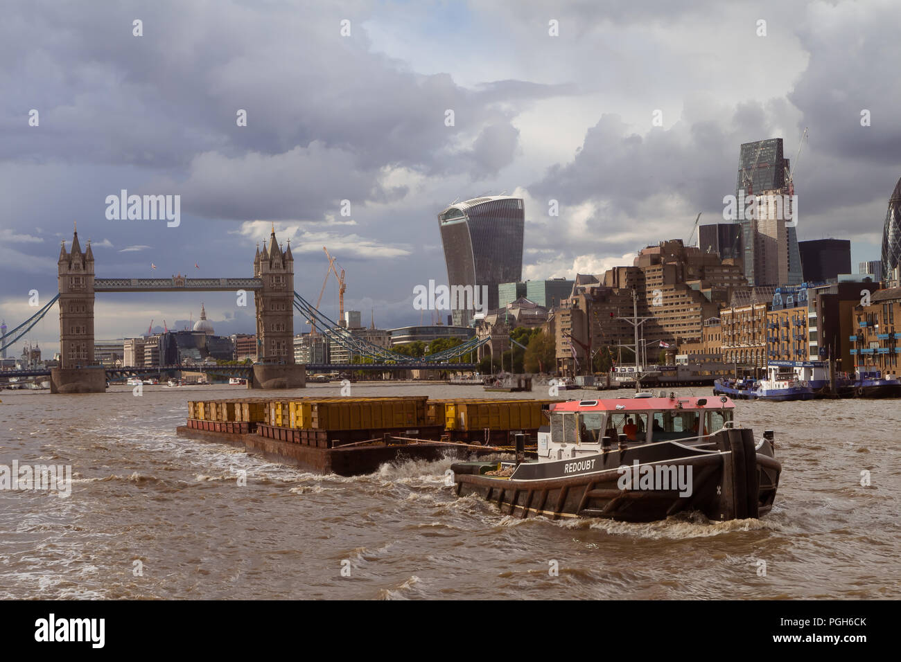 September 2017, River Thames, London, UK - tugboat tow barges with yellow containers full of household waste; use of river transport reduces congestio Stock Photo