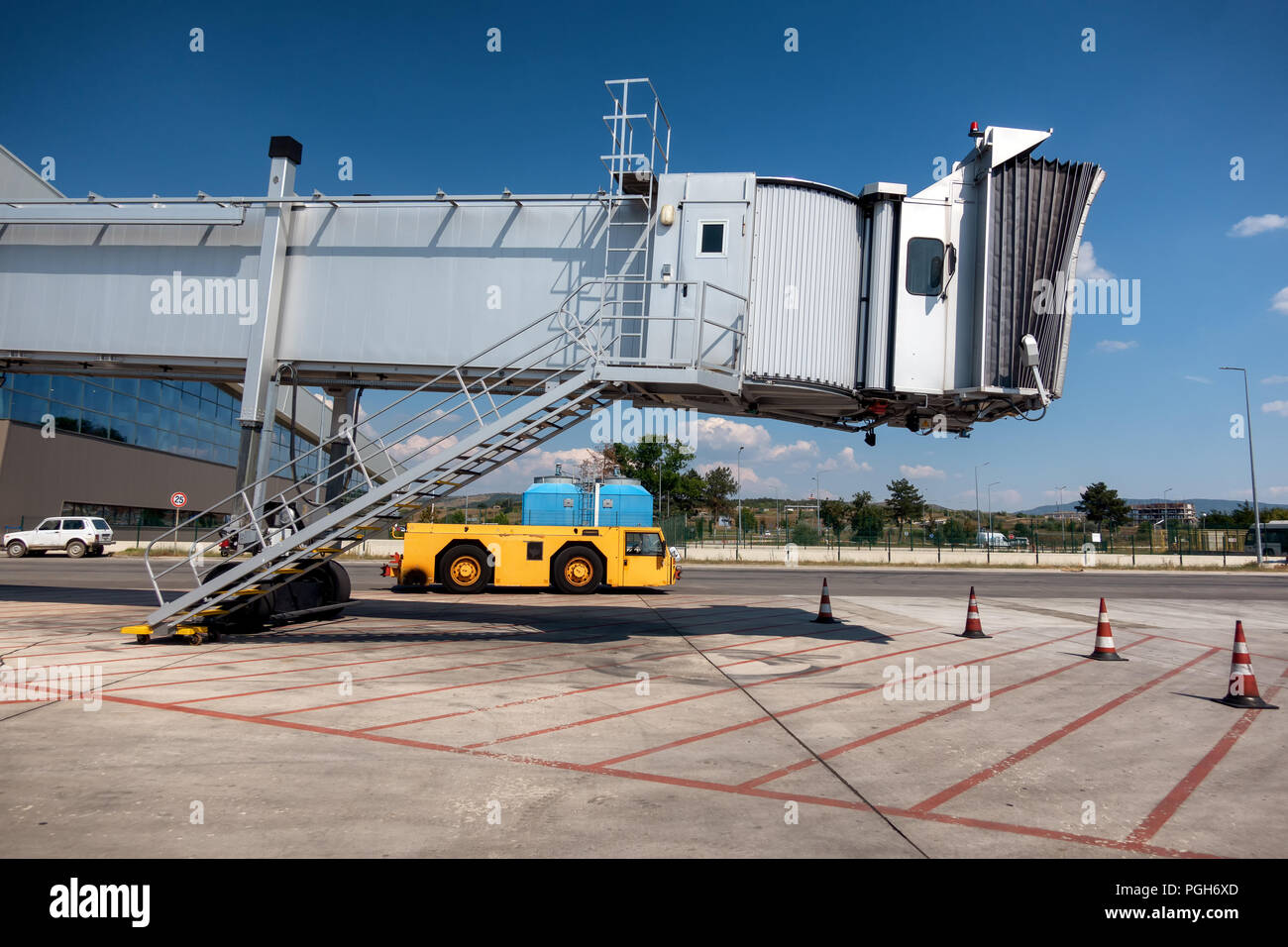 Jet bridge, boarding bridge on airport with yellow tow tractor beneath Stock Photo