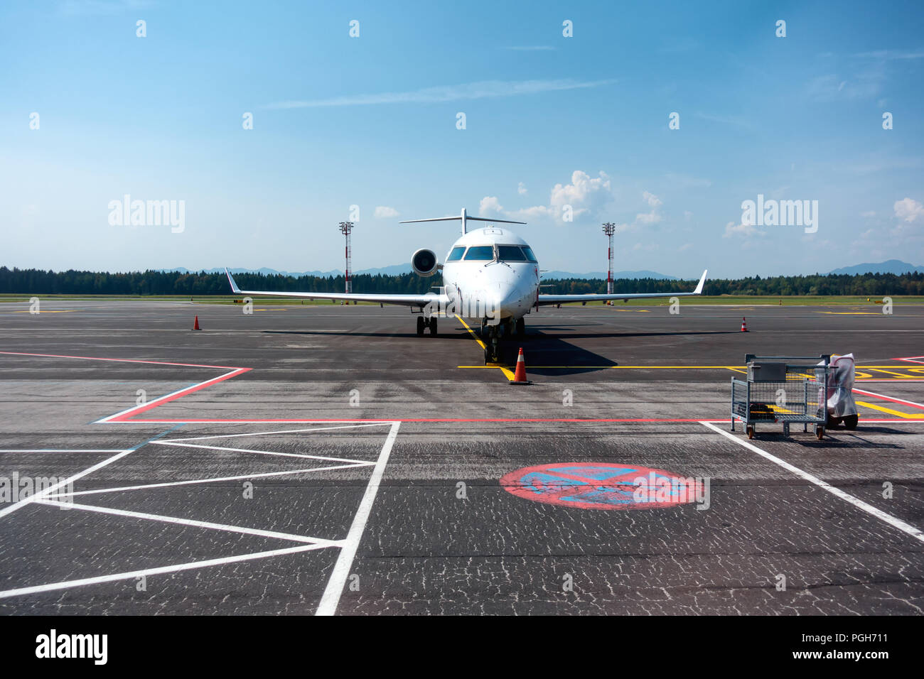 Small business, commuter jet airplane on airport, head on with apron markings on ground, copyspace Stock Photo