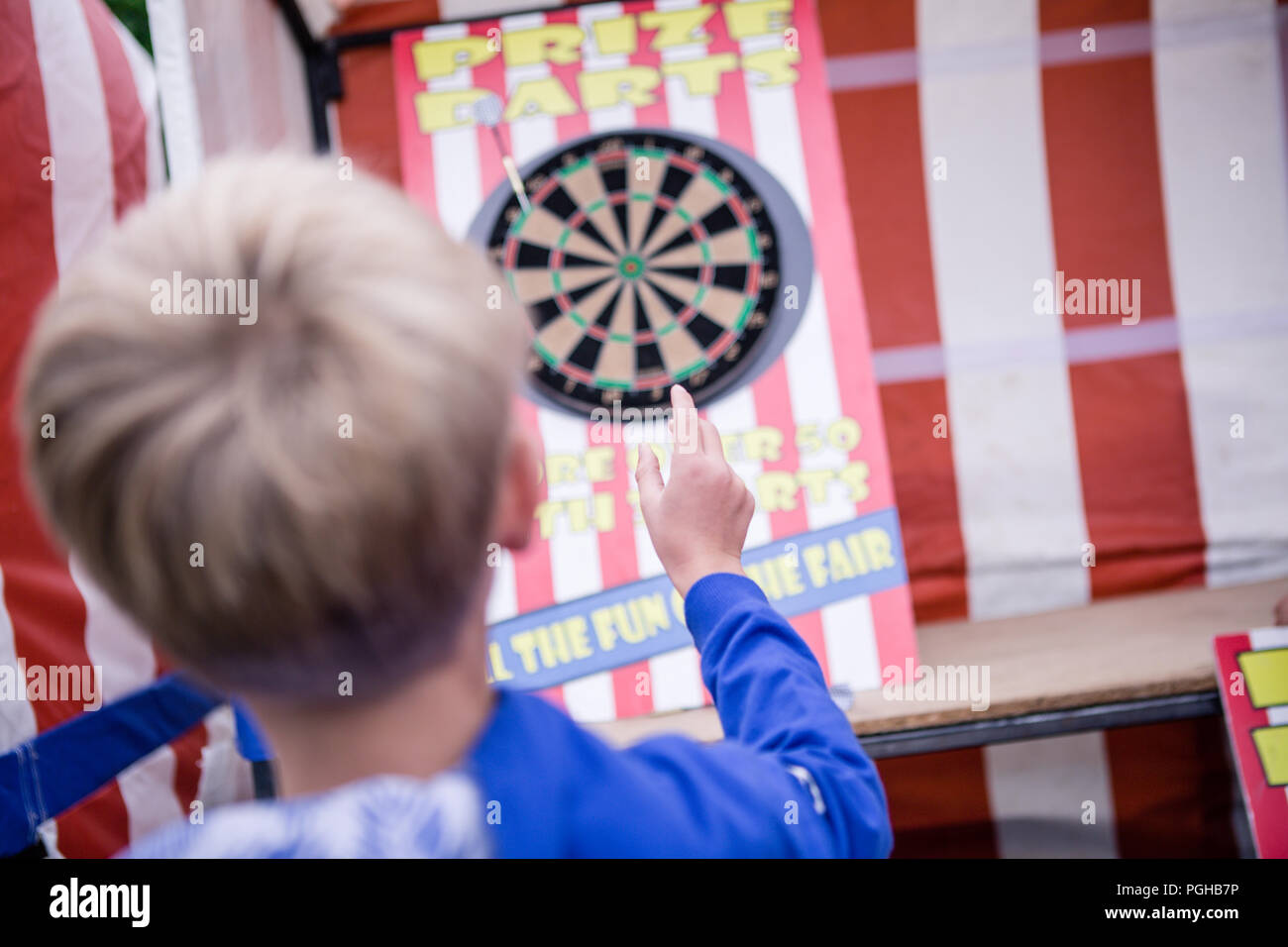 Young European boy throwing dart in mid air, back of head Stock Photo