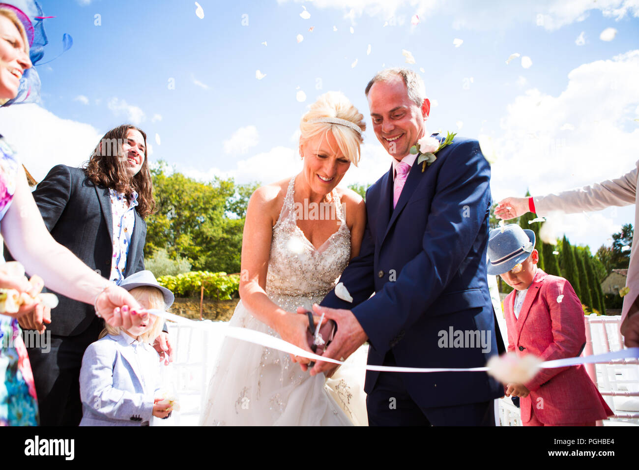 Mature Caucasian Couple Cutting Ribbon At Wedding In French