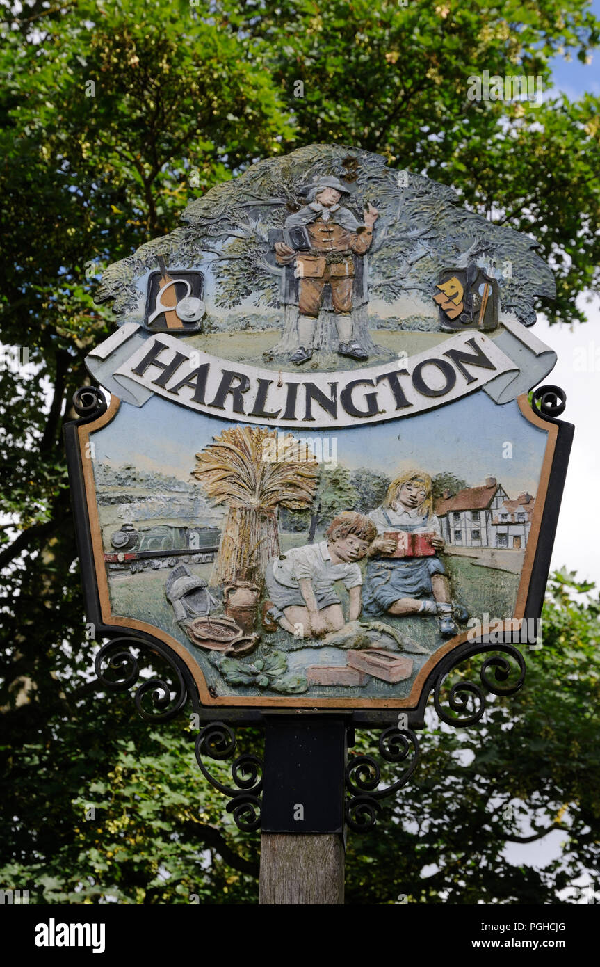 Village Sign, Harlington, Bedfordshire. Elements in the design portray Harlington’s history,  including John Bunyan preaching under the oak tree. Stock Photo