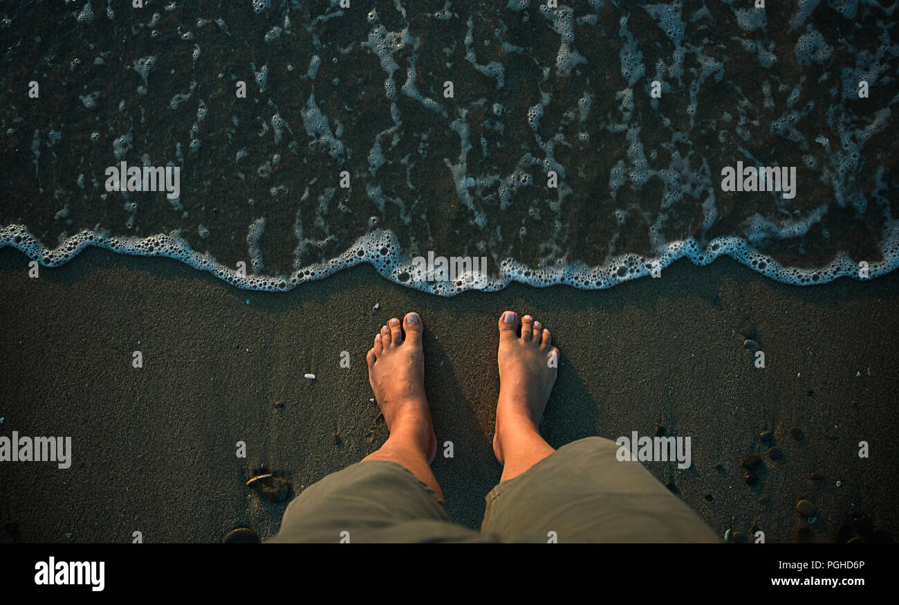 Headshot of man's feet on sandy beach Stock Photo
