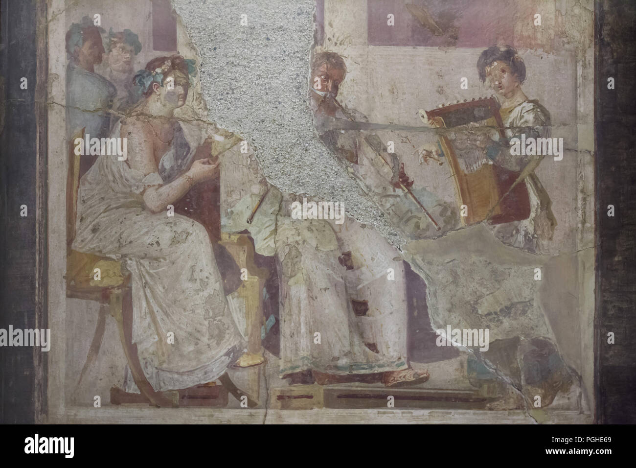 Ancient Roman musicians depicted in the Roman fresco from Herculaneum (1-79 AD), now on display in the National Archaeological Museum (Museo Archeologico Nazionale di Napoli) in Naples, Campania, Italy. Seated woman appears to be reading the musical score being played by the musicians on a tibia (Roman double flute) and a cithara (Roman lyre). Stock Photo